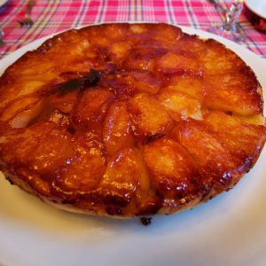 Tarte Tatin caramélisée sur une assiette blanche.
