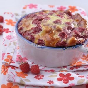 Clafoutis aux framboises, servi sur une serviette fleurie.