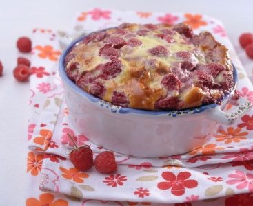 Clafoutis aux framboises, servi sur une serviette fleurie.