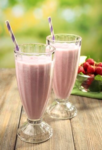 Milkshakes aux framboises avec pailles rayées sur table bois