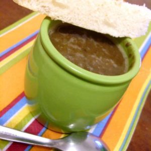 Soupe dans un bol vert avec pain et cuillère.