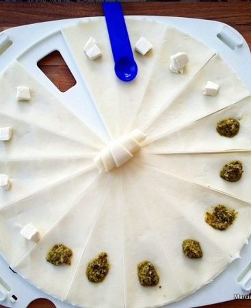 Préparation de croissants apéritifs au pesto et fromage.