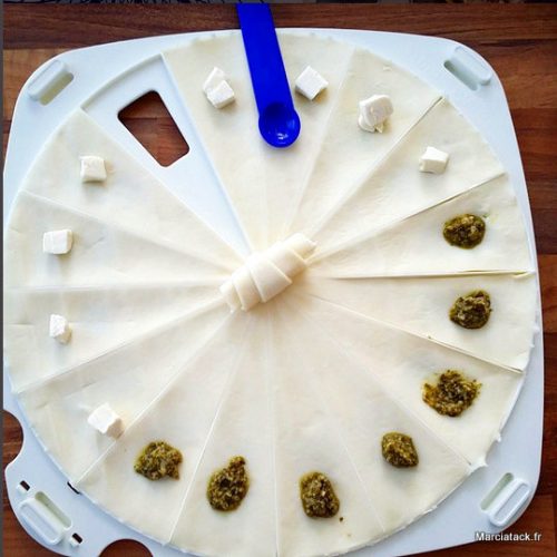 Préparation de croissants avec fromage et pesto sur plateau.