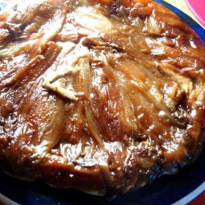 Tarte tatin d'oignons caramélisés sur une assiette bleue.