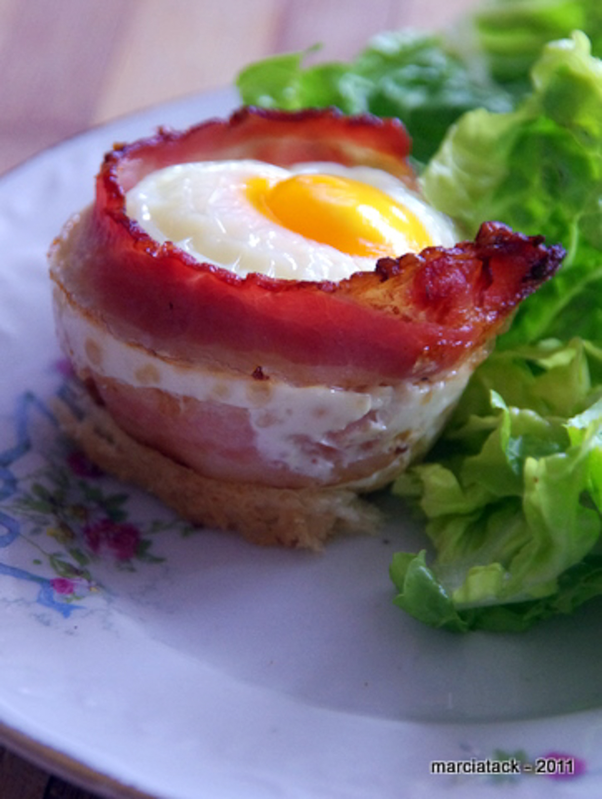 Œuf au bacon et salade verte sur assiette.