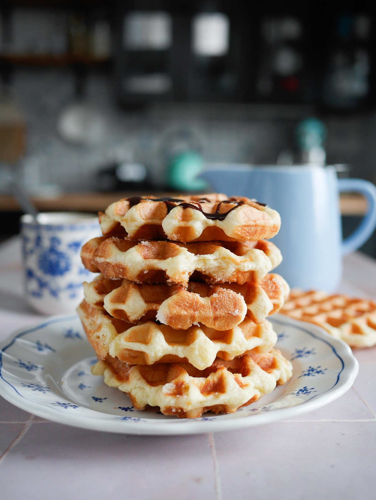 Pile de gaufres avec chocolat, tasse et pot bleu.