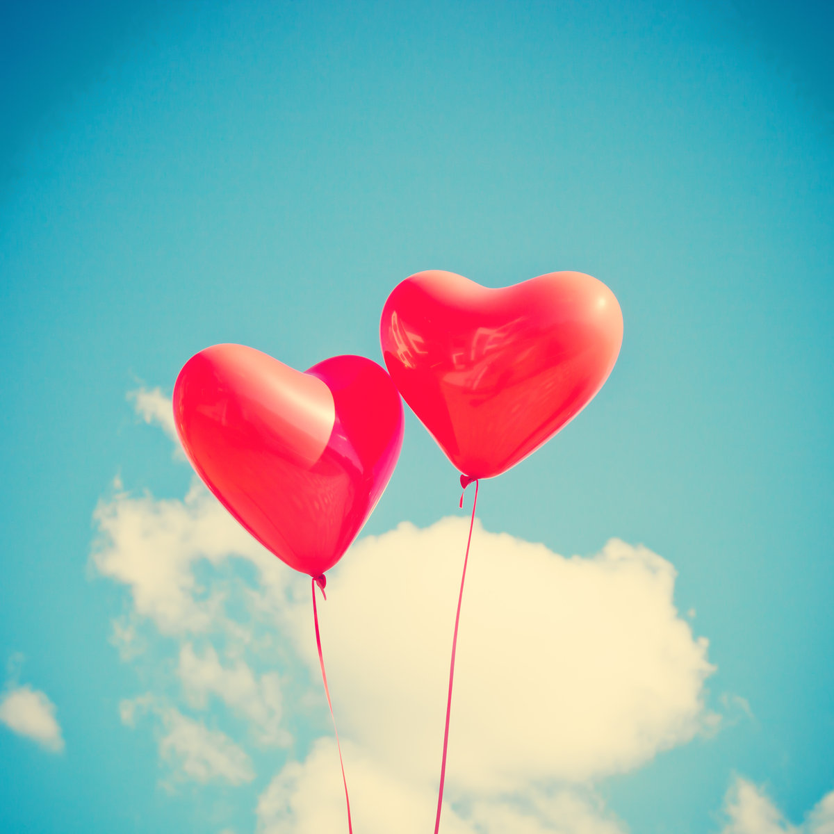 Deux ballons rouges en forme de cœur dans le ciel.