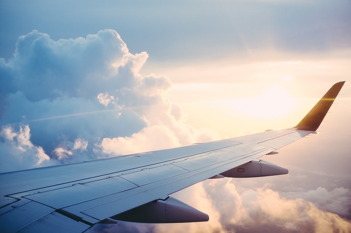 Vue d'avion: aile au-dessus des nuages au coucher du soleil