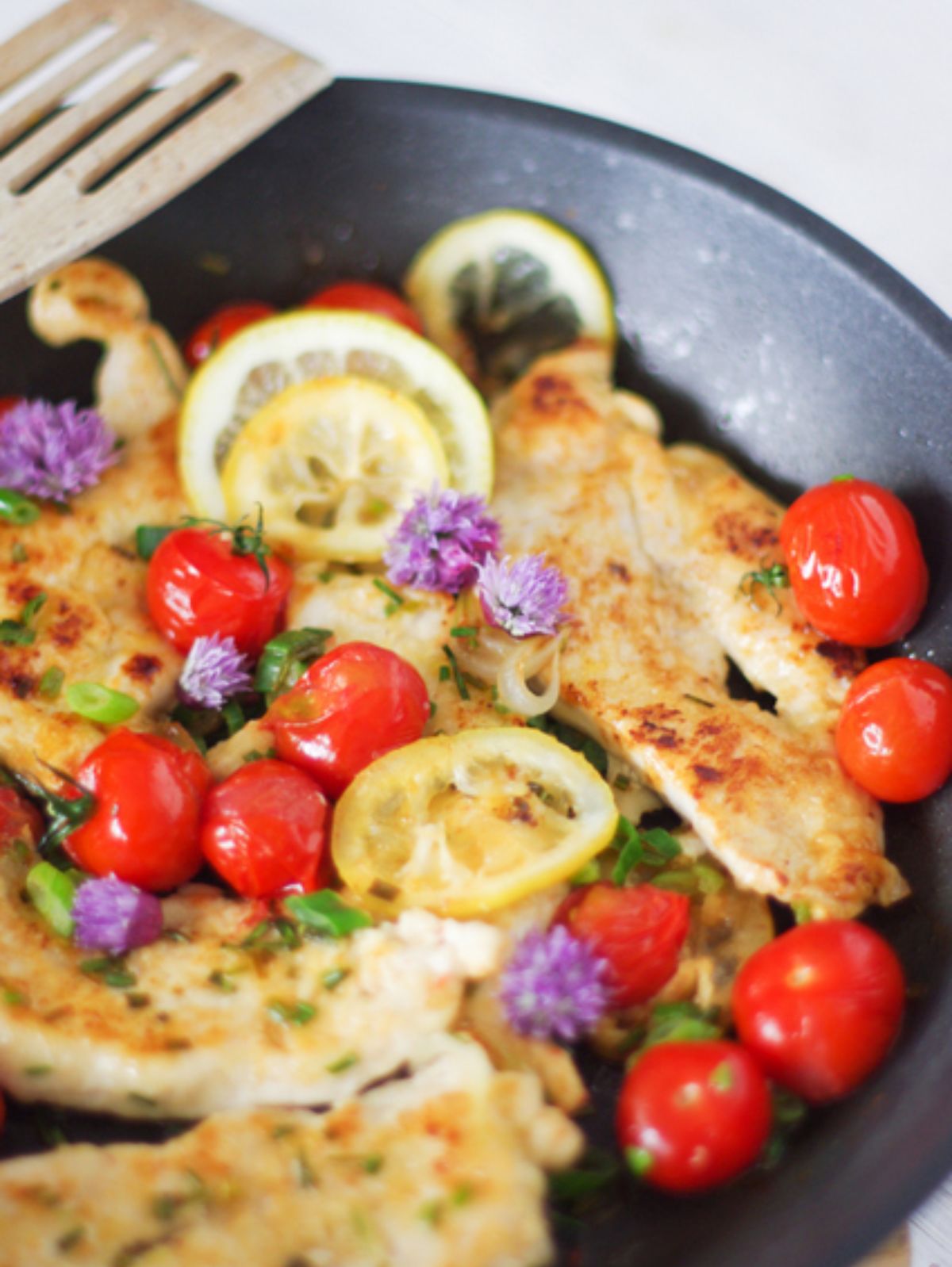 Escalopes de poulet, tomates cerises et citron à la poêle.
