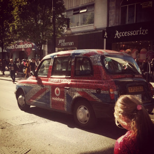 Taxi londonien décoré Union Jack, slogan et Vodafone