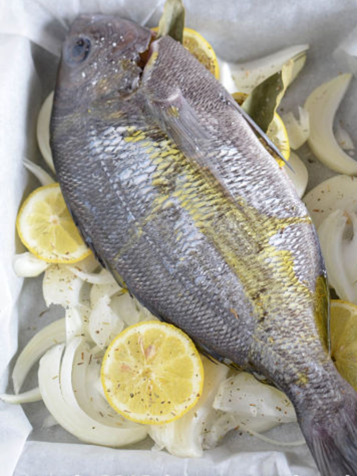Poisson entier prêt à cuire avec citron et oignon.