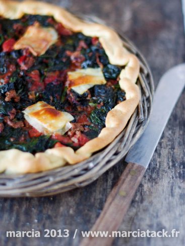 Tarte épinards, tomate et fromage sur panier en osier.