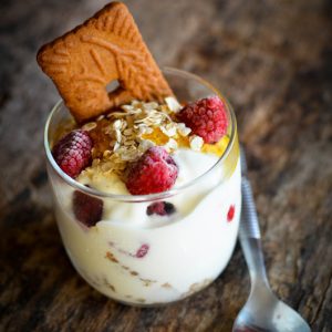 Dessert yaourt, framboises, granola, spéculoos dans un verre.