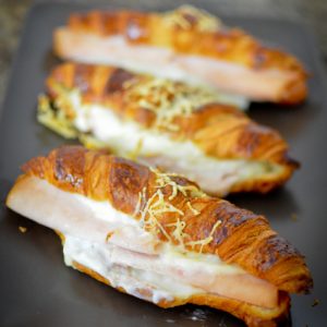 Croissants jambon fromage gratinés sur plateau, vue rapprochée.