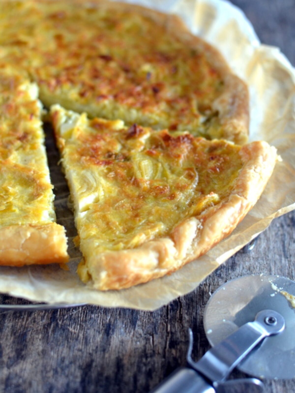 Tarte aux oignons tranchée, fond croustillant sur papier cuisson.