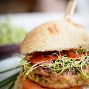 Burger végétarien avec tomates et graines germées.