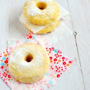 Beignets moelleux saupoudrés de sucre glace sur tissu fleuri.