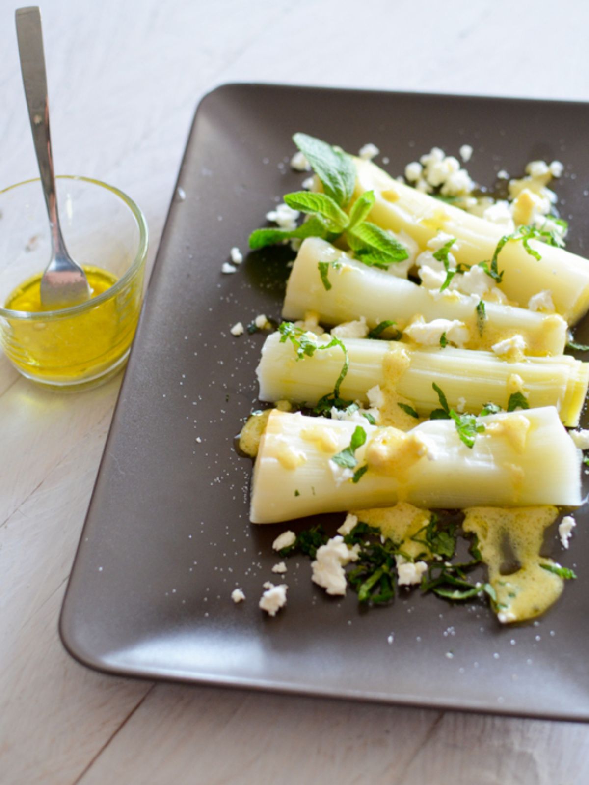 Poireaux vinaigrette, féta et menthe sur assiette.