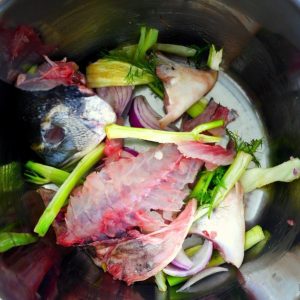 Déchets de poisson et légumes dans une casserole inox.