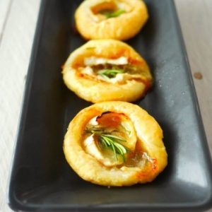 Mini-tartes feuilletées au chèvre et romarin sur plat noir.
