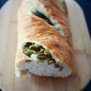Pain aux olives sur planche à découper en bois.