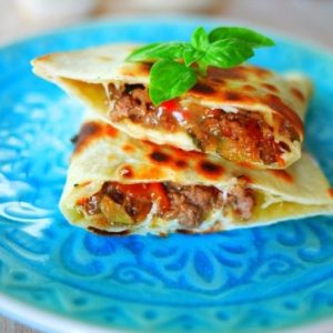 Quesadilla de bœuf sur assiette bleue avec basilic.