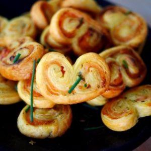Palmiers feuilletés salés, apéritif délicieux sur plateau noir.
