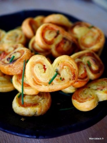 Palmiers feuilletés salés, apéritif délicieux sur plateau noir.