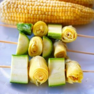 Brochettes de maïs et courgettes grillées sur assiette.
