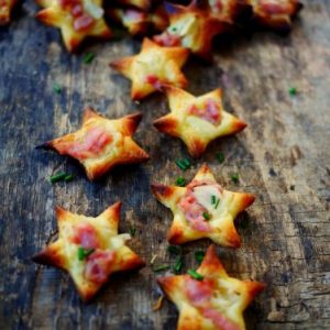 Mini-pizzas étoiles au jambon sur planche en bois.