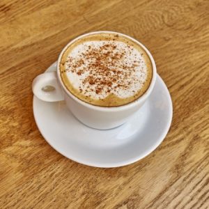Cappuccino avec cannelle sur table en bois.