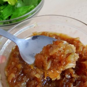 Confiture d'oignons maison, persil frais en arrière-plan.