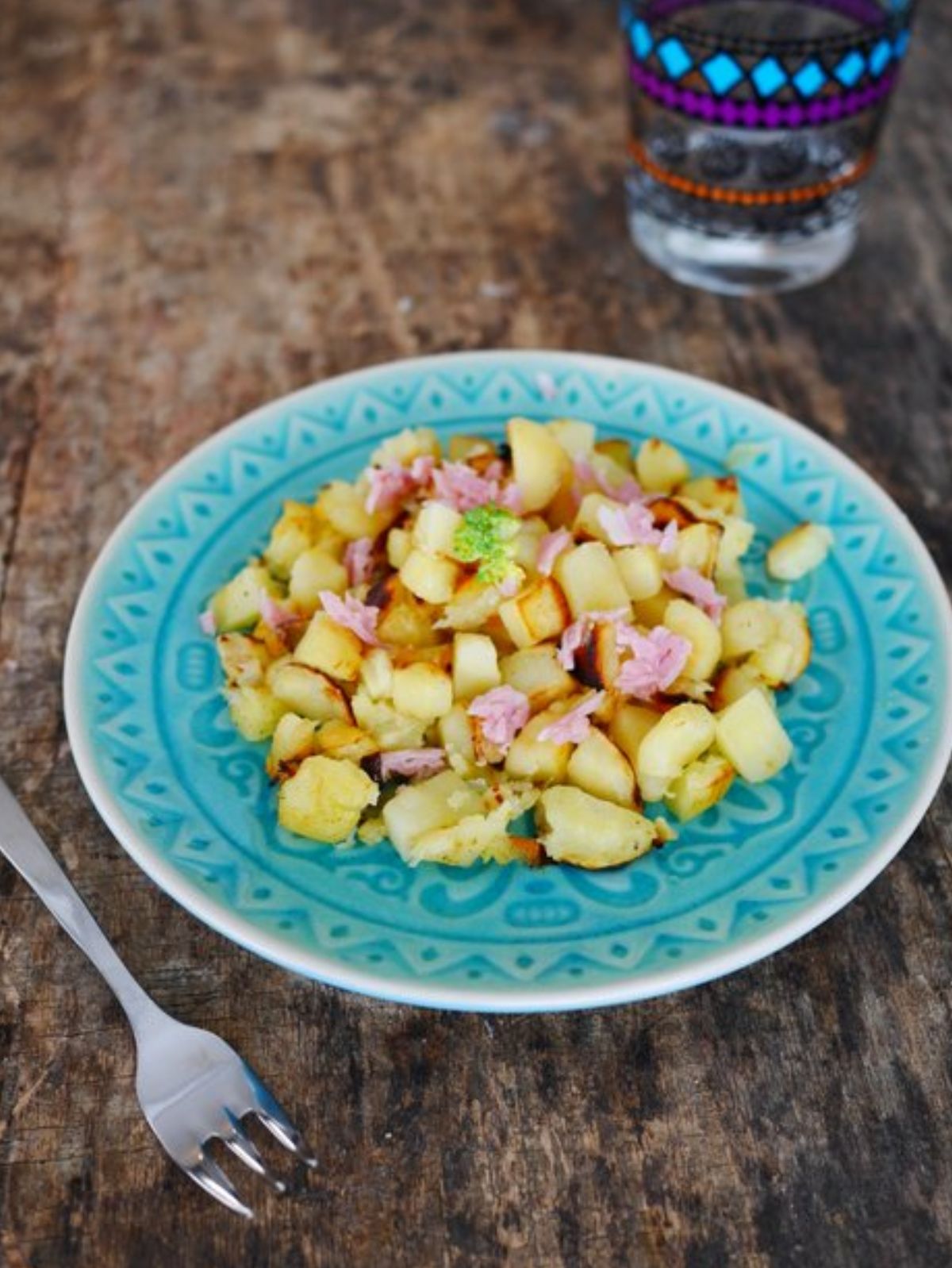 Pommes de terre sautées avec jambon sur assiette bleue.