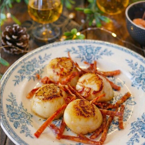 Coquilles Saint-Jacques poêlées et lardons sur assiette décorée.