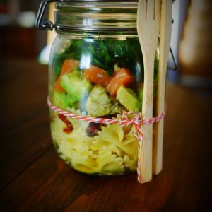 Salade de pâtes en bocal avec couverts en bois.