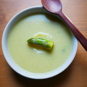 Bol de crème d'asperges avec cuillère en bois.