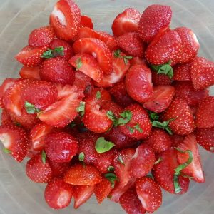 Salade de fraises fraîches avec quelques feuilles de basilic.