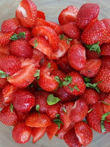 Salade de fraises fraîches avec quelques feuilles de basilic.