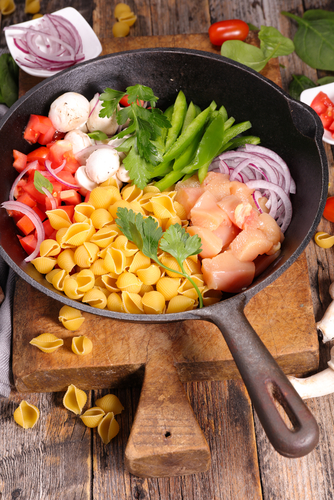 Ingrédients pâtes : poulet, légumes, coquillettes dans poêle.