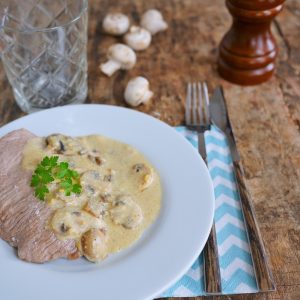 Escalope de veau sauce champignons sur table en bois.