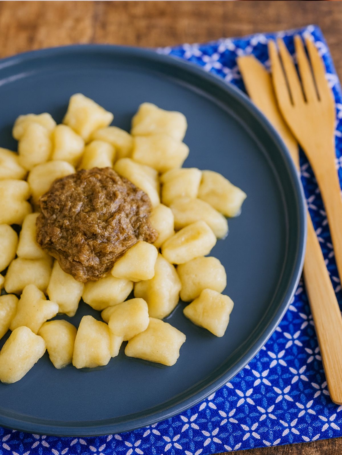 Assiette de gnocchis avec sauce, fourchettes en bois.