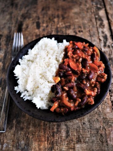 assiette de chili corn carne au cumin et épices, servie avec maïs et riz