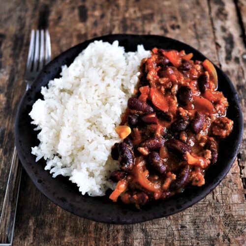 assiette de chili corn carne au cumin et épices, servie avec maïs et riz