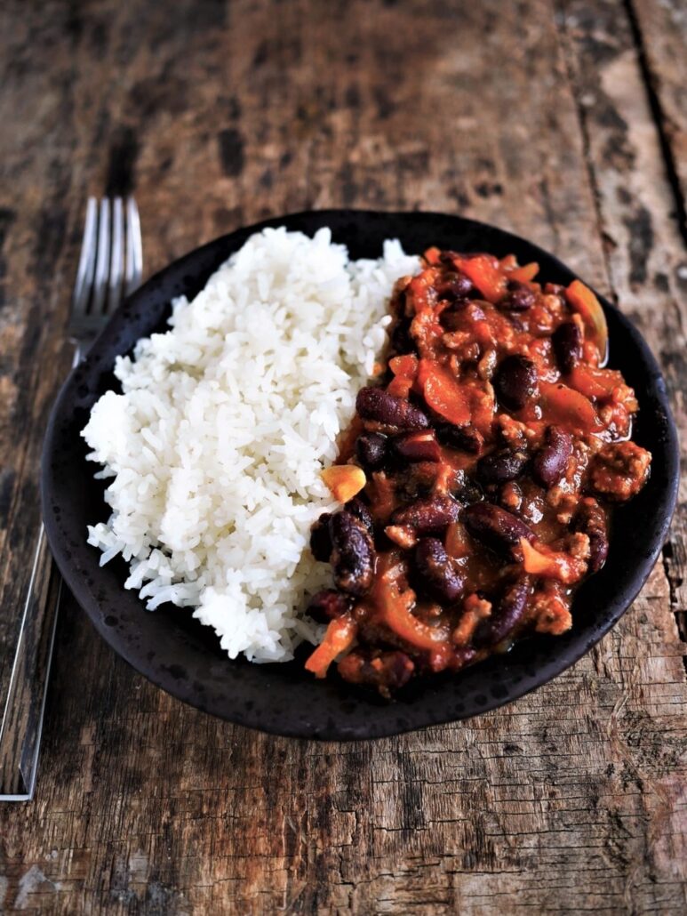 assiette de chili corn carne au cumin et épices, servie avec maïs et riz