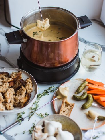 Fondue au fromage avec pain, légumes et vin.