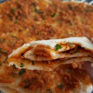 Lahmacun coupé montrant la garniture, prêt à manger