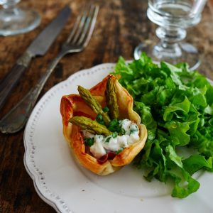 Tartelette asperges, salade verte, sur assiette blanche.