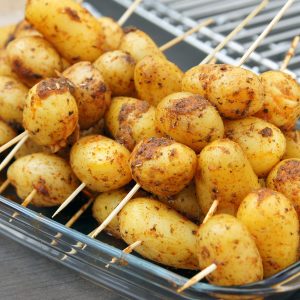 Brochettes de petites pommes de terre assaisonnées, prêtes à griller.