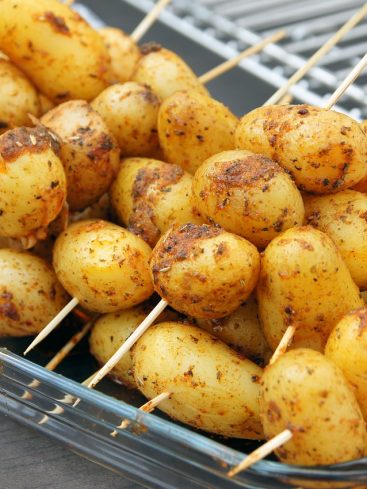 Brochettes de petites pommes de terre assaisonnées, prêtes à griller.