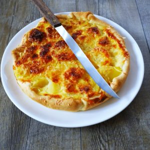 Tarte aux pommes de terre coupée avec un couteau.